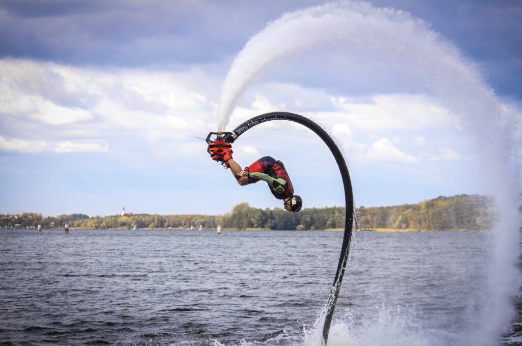 Flyboard - mężczyzna unosi się w powietrzu na latającej desce i wykonuje akrobacje