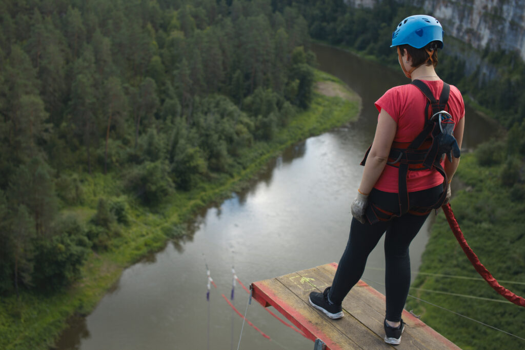 Kobieta w uprzęży. Stoi na platformie. Czeka na wykonanie skoku na bungee.